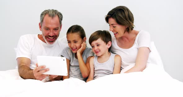 Family using digital tablet in bedroom