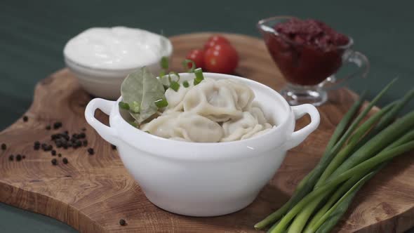 Traditional Russian Dumplings Served in Wooden Raw Board Over Green Background Table