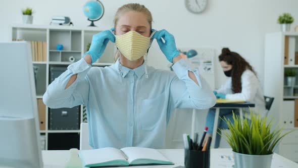 Portrait of Beautiful Young Businesswoman Putting on Reusable Face Mask in Office alt
