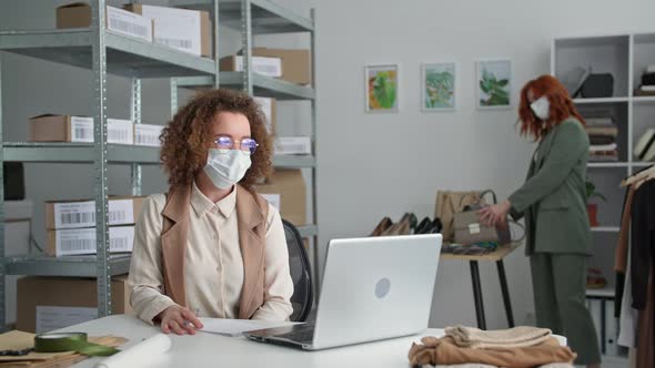 Online Shop Young Woman in Medical Masks Seller and Her Female Colleague Sell Goods Via Internet and