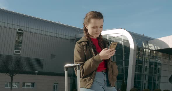 A Young Girl Is Looking on Her Phone. She Is Waiting for the Plane Arrival . Beautiful Smile. Sunny