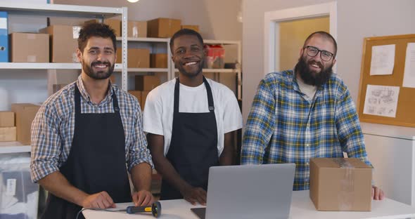 Happy Multiethnic Entrepreneurs Smiling at Camera Standing in Small Warehouse