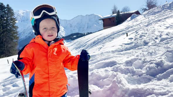 Boy 3 Years Old Child with Ski Over Mountains on Background