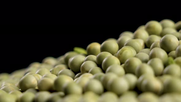 Uncooked dried whole green peas on black. Macro