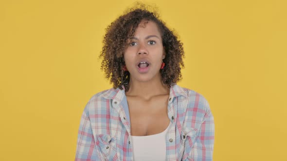 Young African Woman Feeling Shocked on Yellow Background