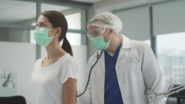 An Experienced Therapist Listens to the Lungs of His Patient a Woman with Symptoms of Coronavirus