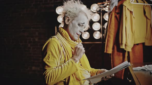 Mime with Makeup Crosses Out Lines in Script with Pencil