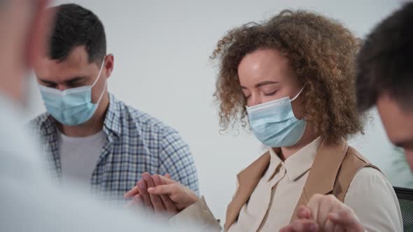 Portrait of Young Woman in Medical Mask Holds Hands of Men By Sides During Collective Prayer at