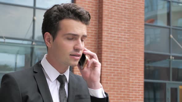 Angry Businessman Talking on Phone While Walking to Office