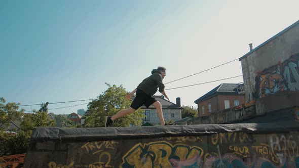 Young athletic guy runs and jumps somersaults on the roofs