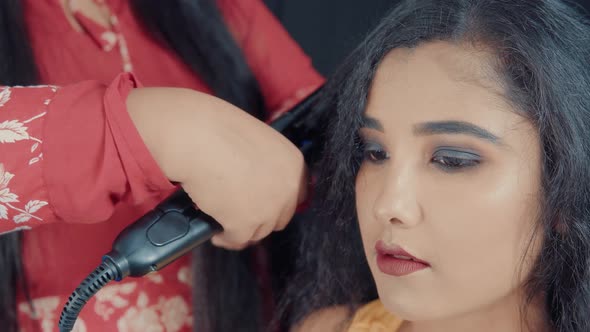 Close up of beautiful young woman with make up and hairdresser making her a hairstyle