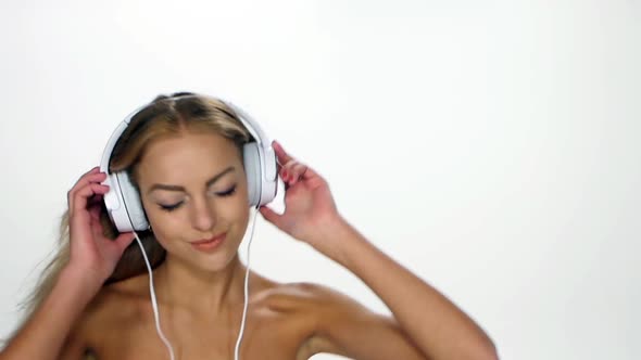 Beautiful Female in Headphones Listening To the Music with Fluttering on the Wind Hair Over White