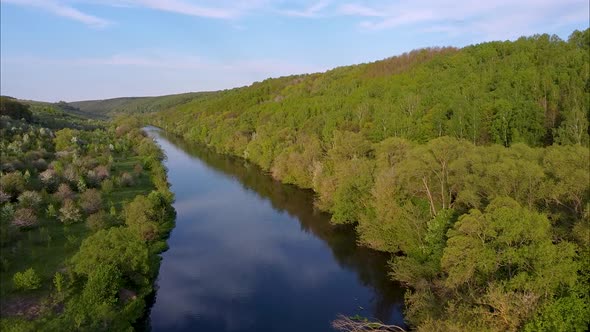 View of the river from above. Flight over water and forest trees from a height