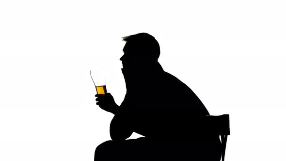 Man Drinks Beer From a Glass. Side View. Silhouette White Background