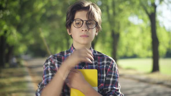 Intelligent Nerd Teenage Boy Adjusting Eyeglasses Looking at Camera Smiling