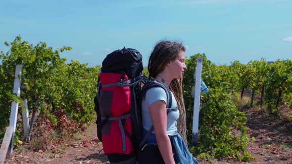 Girl with Dreadlocks Goes Past Vineyards