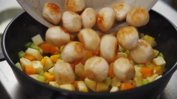 Crop person adding meatballs to stew