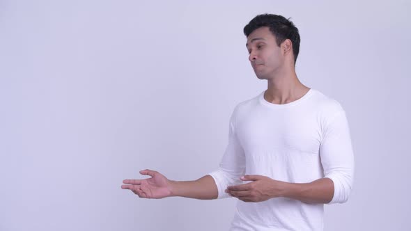 Happy Young Indian Man Showing Something and Giving Thumbs Up