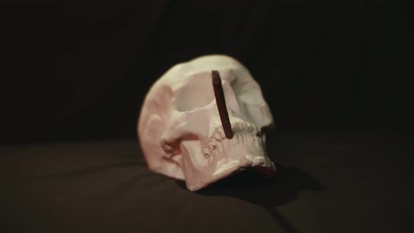 Human Skull with Smoking Cigarette in Mouth on Dark Background