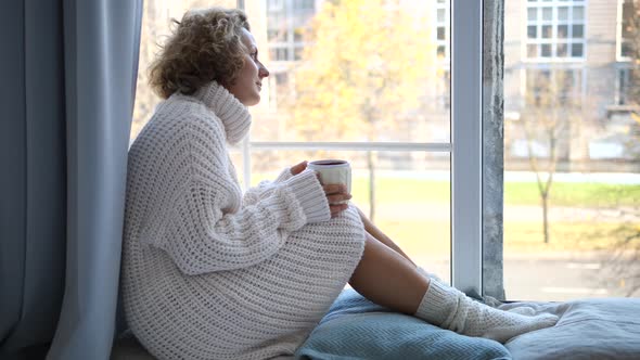 Lonely Woman Sitting By The Window With Cup