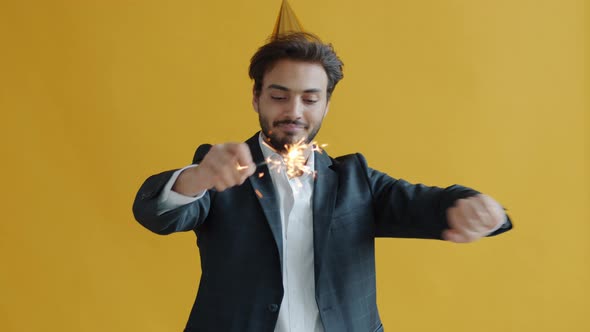 Happy Arab Guy Wearing Party Hat Dancing with Bengal Light Enjoying Holiday