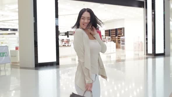 Happy young woman spins around with her shopping bags at mall