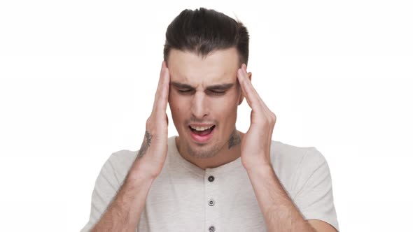 Headshot of Caucasian Man with Stubble and Tattoo on Body Rubbing Temples Because of a Headache