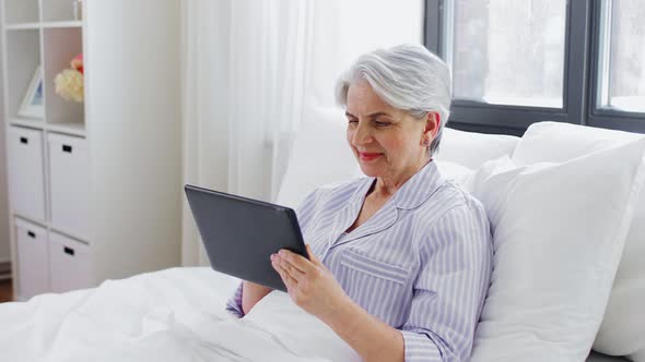 Senior Woman with Tablet Pc in Bed at Home Bedroom