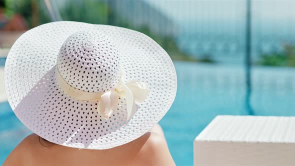 Rear View Woman in Elegant Sun Hat Enjoying Vacation Sunbathing and Drinking Red Wine