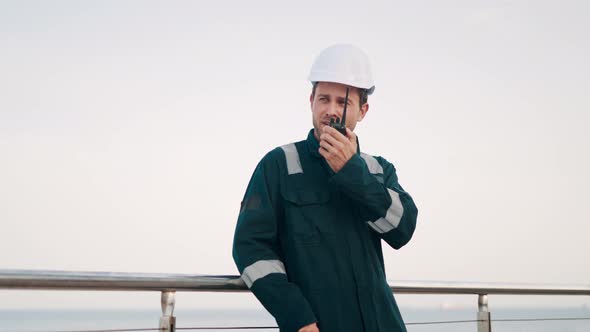 Port Worker Talking on Walkietalkie Radio While Doing Cargo Logistics Control in Seaport