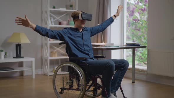 Smiling Happy Disabled Man in VR Headset Enjoying Augmented Reality Sitting in Wheelchair at Home