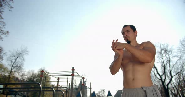 Man Is Doing Hand Warm-up Before Training on the Sport Area in Sunny Weather 