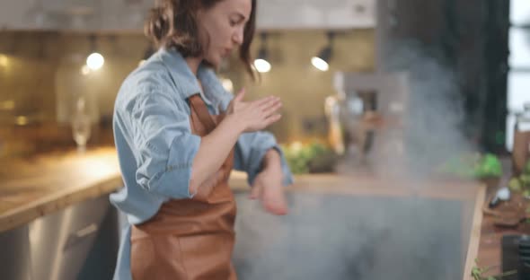 Housewife Hurries on the Kitchen with a Smoke From Burning Food