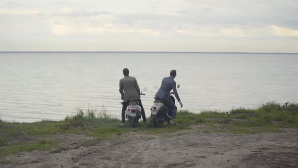 Extreme Wide Shot of Two Confident Elegant Men Getting Off Scooters and Looking at Picturesque