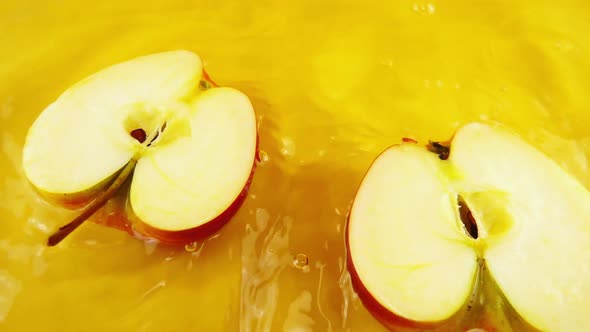 Rotating segment of a ripe and juicy apple on an orange background. Slow motion.