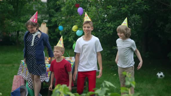 Group of Joyful Children Jumping Up Having Fun at Birthday Party on Backyard