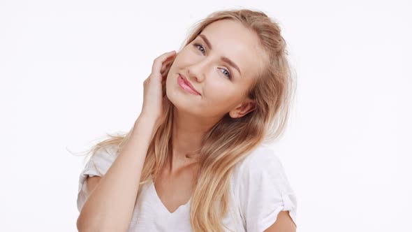 Young Beautiful Caucasian Blonde Girl Smiling Touching Hair Showing Ear on White Background