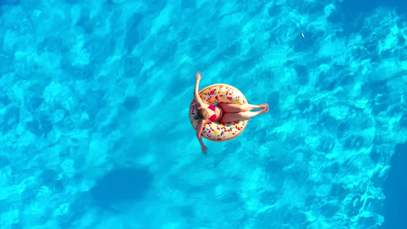 Aerial View of a Woman in Red Swimsuit Lying on a Donut in the Pool