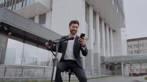 Modern Businessman in a Suit Looking at the Navigation Map on His Phone with Scooter