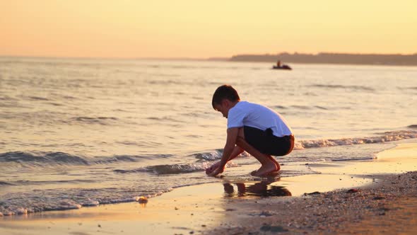 Boy plays in sea water in the evening