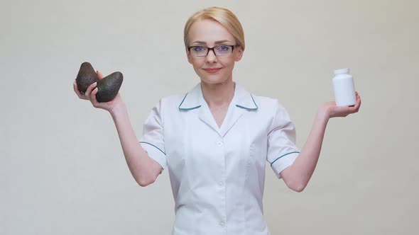 Nutritionist Doctor Holding Organic Avocado Fruit and Jar of Medicine or Vitamin or Omega 3 Capsules