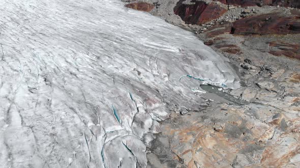 Aerial: terminus of glacier, toe of glacier in frozen mountain alpine landscape