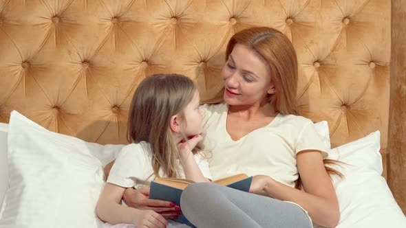 Attractive Woman Enjoying Reading a Book with Her Adorable Little Daughter