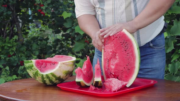 A Farmer Man at a Round Table Cuts a Watermelon