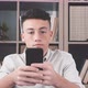 Happy young man using his smartphone at home surfing the net doing homework having fun - VideoHive Item for Sale