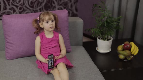 Little Child Sitting on Couch While Watching TV. Kid Girl Watch Television