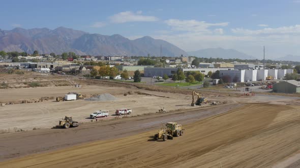 Aerial shot of a road grader and Bulldozer roller compacting and leveling dirt at a construction sit