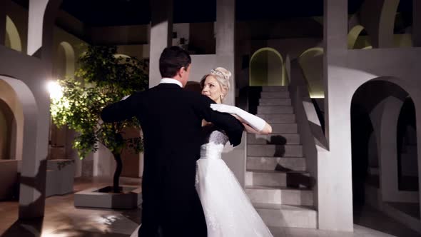 Beautiful Woman in White Gorgeous Dress and Man in Black Tailcoat are Dancing Waltz in Ballroom