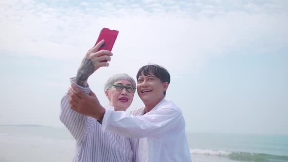A senior woman taking a selfie photo with her partner on the beach.
