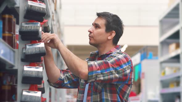 Man 30 Years in a Plaid Shirt in a Hardware Store Chooses Paint Brushes